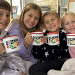 Four kids in pyjamas holding personalised Santa Cousin Crew enamel mugs together on the couch