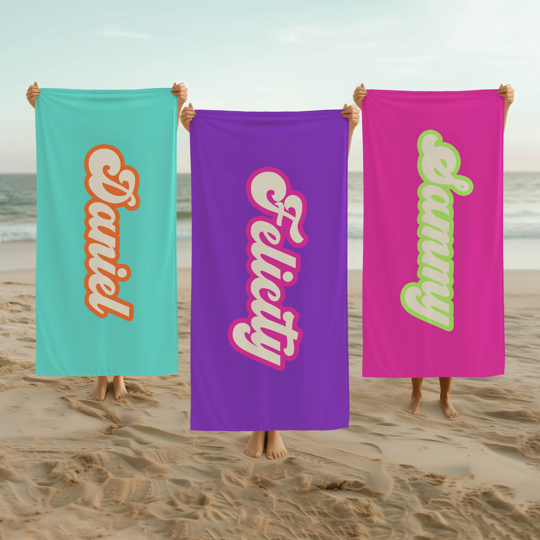Three beach towels with personalized names held by people on a beach.