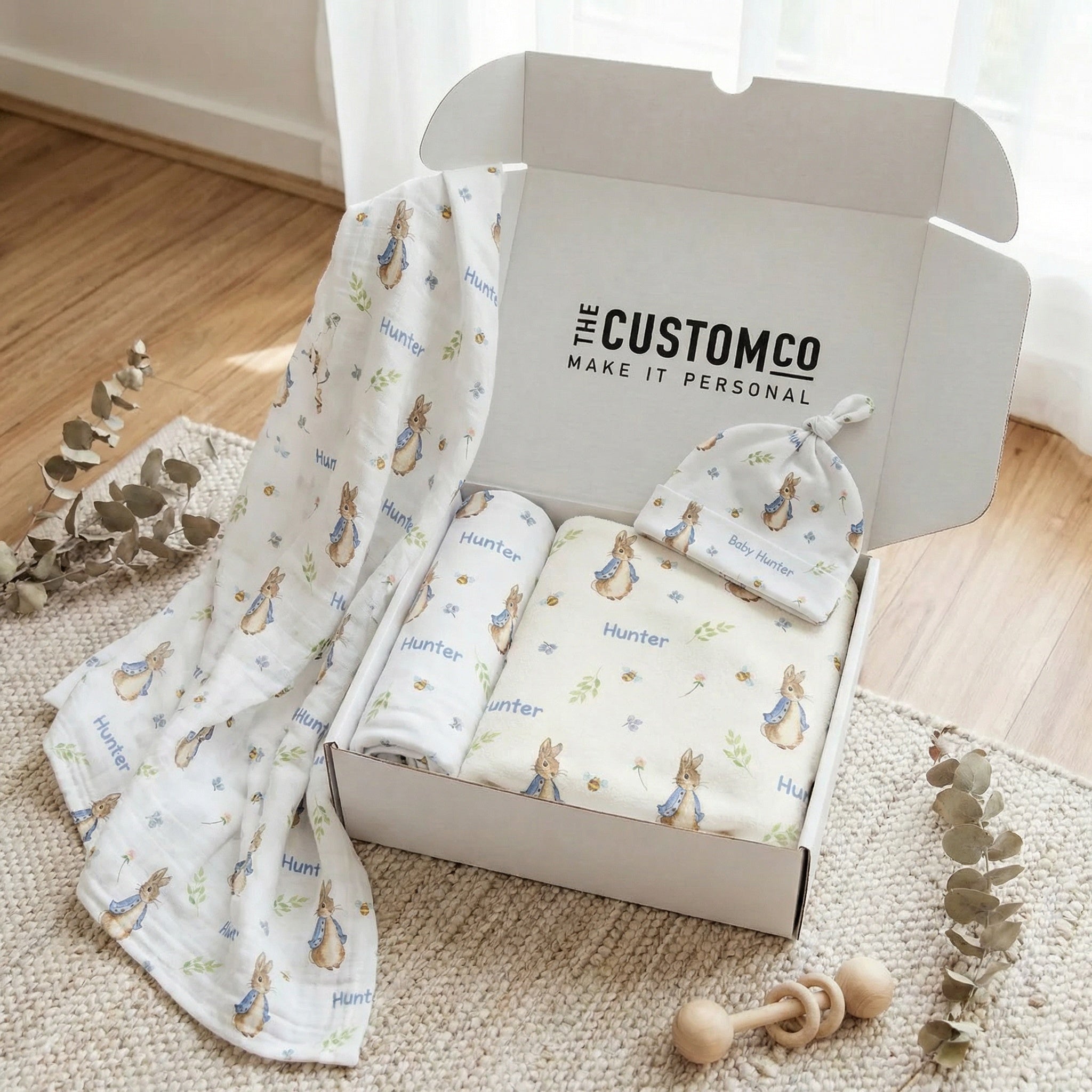 Personalised newborn essentials gift bundle with minky blanket, jersey swaddle, muslin swaddle, nursing cover, and beanie baby box