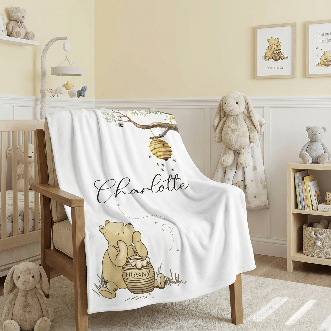 Nursery room with a crib, teddy bears, and a blanket featuring a bear and honey pot design.